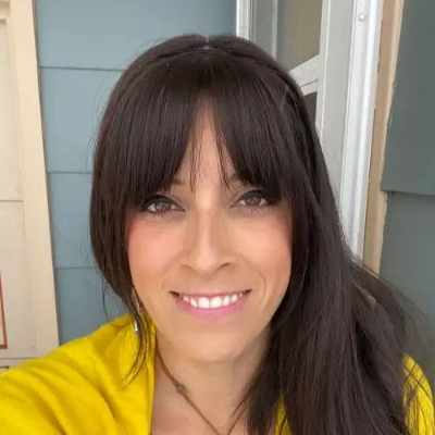 Portrait of Mar Mancha Cisneros in front of a light-colored wall and doorway.